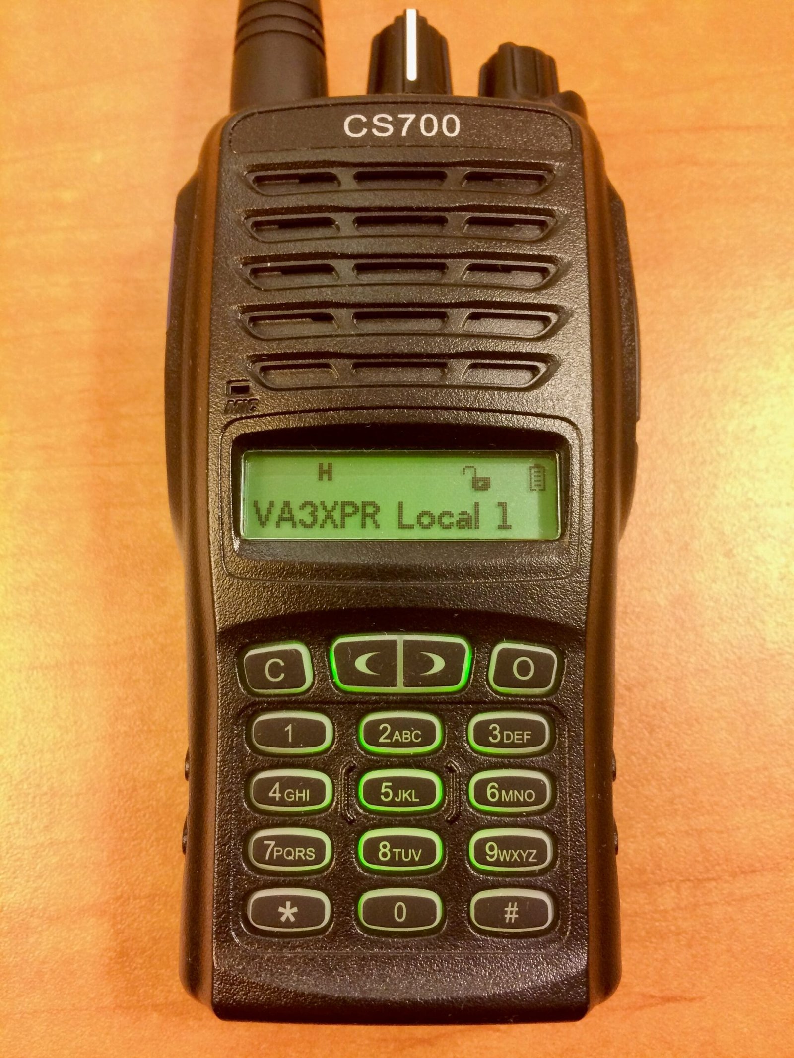 A close-up of the Connect Systems CS700 DMR radio showing its front keypad and monochrome green display with channel information.