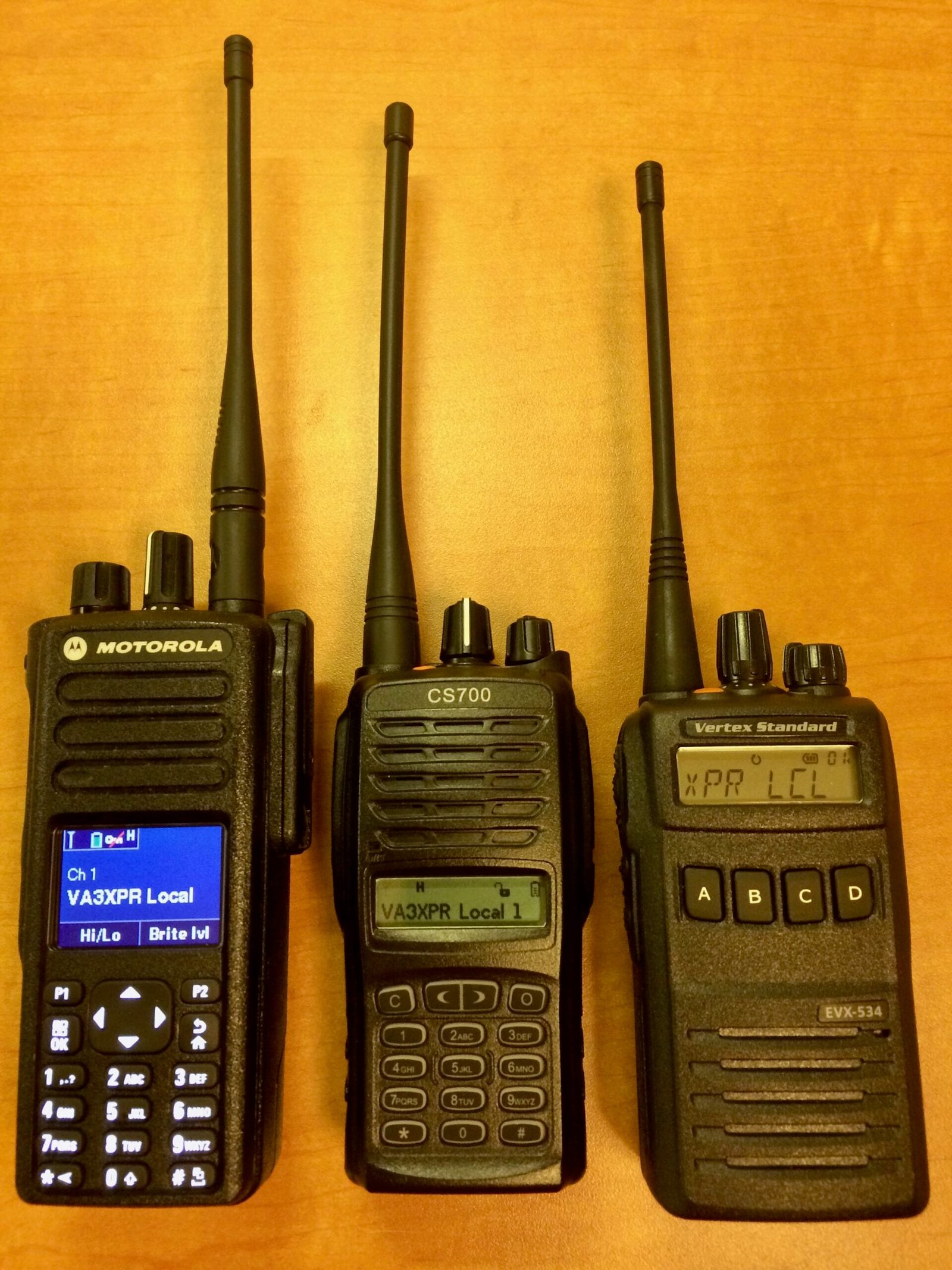 Three DMR radios side by side for comparison: Motorola XPR 7550 on the left, Connect Systems CS700 in the center, and Vertex Standard EVX 534 on the right, highlighting differences in size, keyboards, and displays.