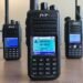 Three budget TYT DMR handheld radios used for digital voice in ham radio, shown on a table with their displays lit.