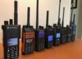 A row of DMR handheld radios from Motorola, Hytera, AnyTone, BFDX, and Radioddity displayed on a desk - perfect for illustrating What Is DMR in Ham Radio.