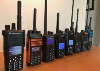 A row of DMR handheld radios from Motorola, Hytera, AnyTone, BFDX, and Radioddity displayed on a desk - perfect for illustrating What Is DMR in Ham Radio.