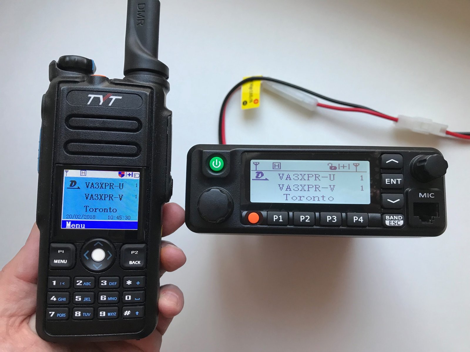 TYT MD-9600 dual-band DMR mobile radio beside the TYT MD-2017 handheld, both powered on and displaying channel information.