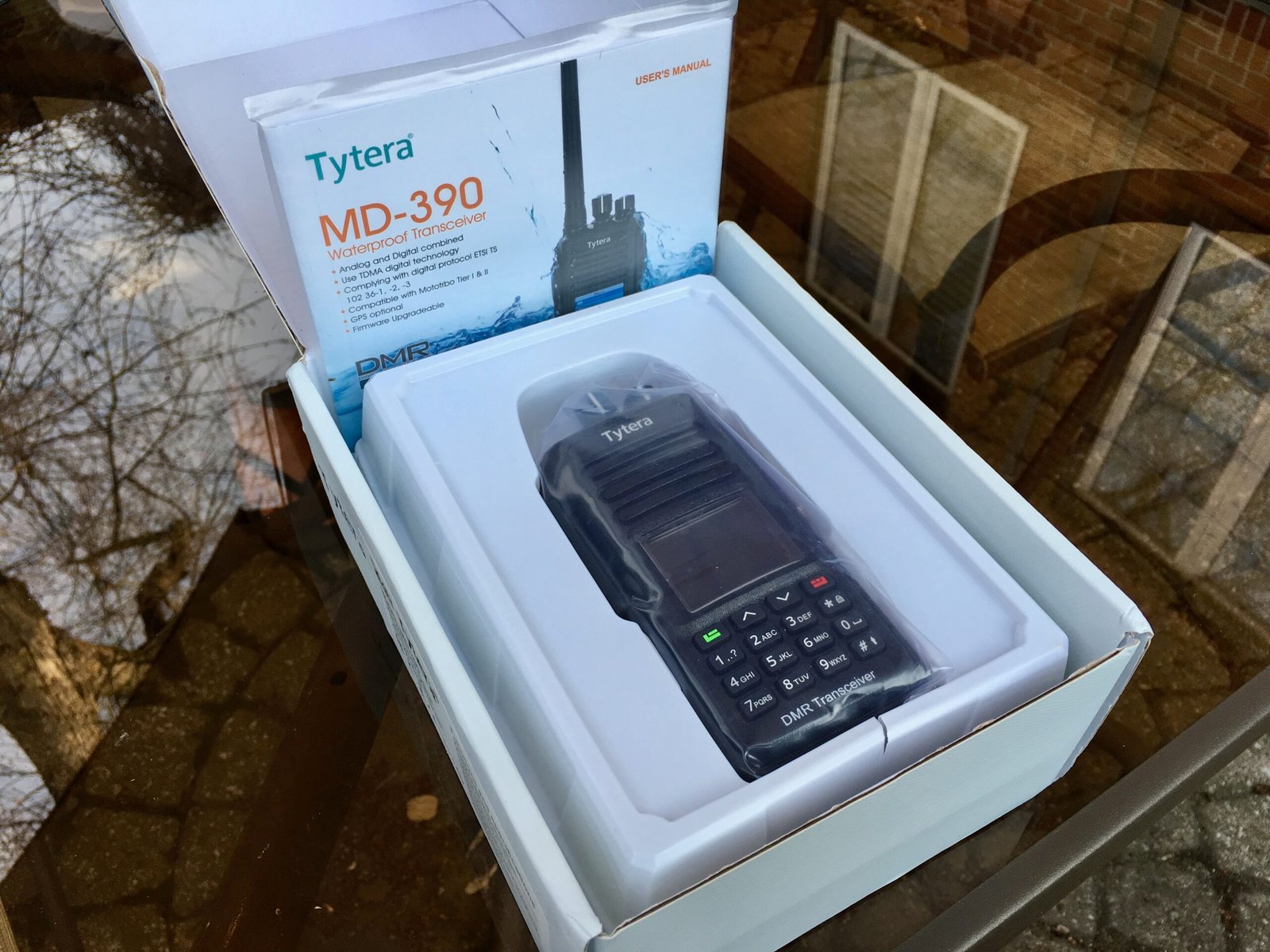 TYT MD-390 waterproof DMR handheld radio inside its retail packaging, with user manual and accessories visible in the box.