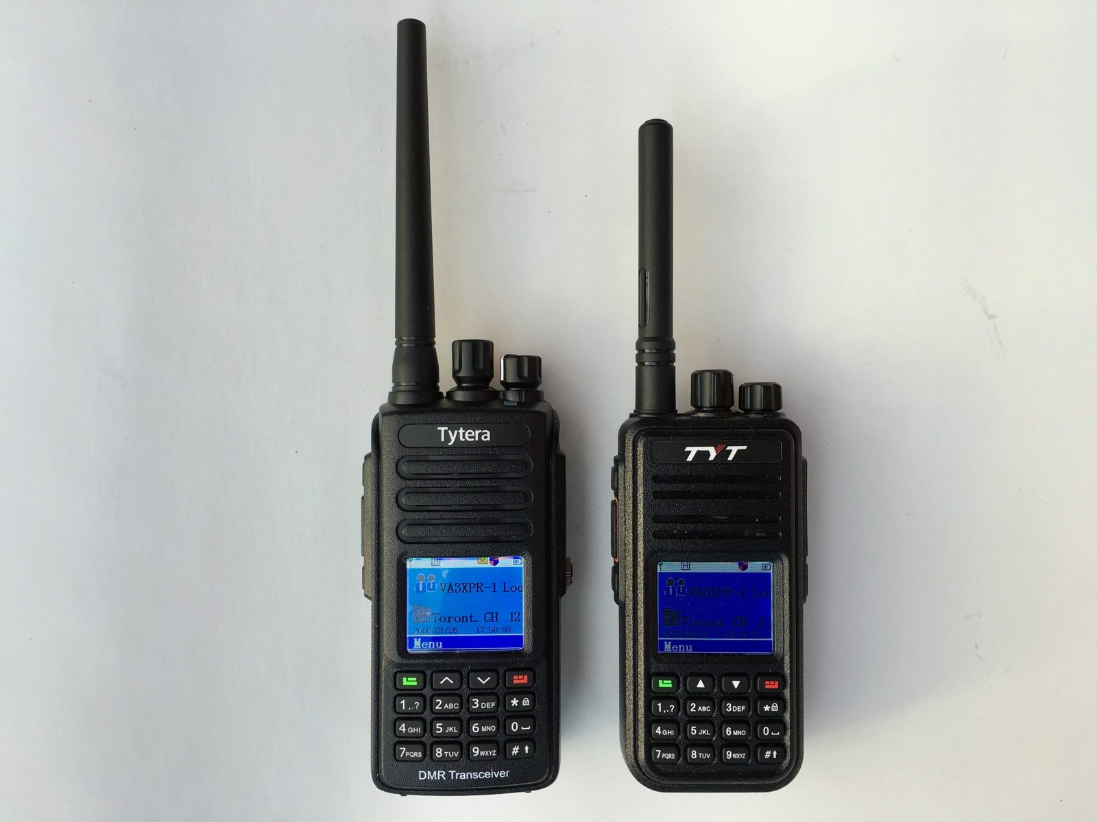 TYT MD-390 and TYT MD-380 DMR handheld radios side by side, showing differences in form factor, antenna length, and display.