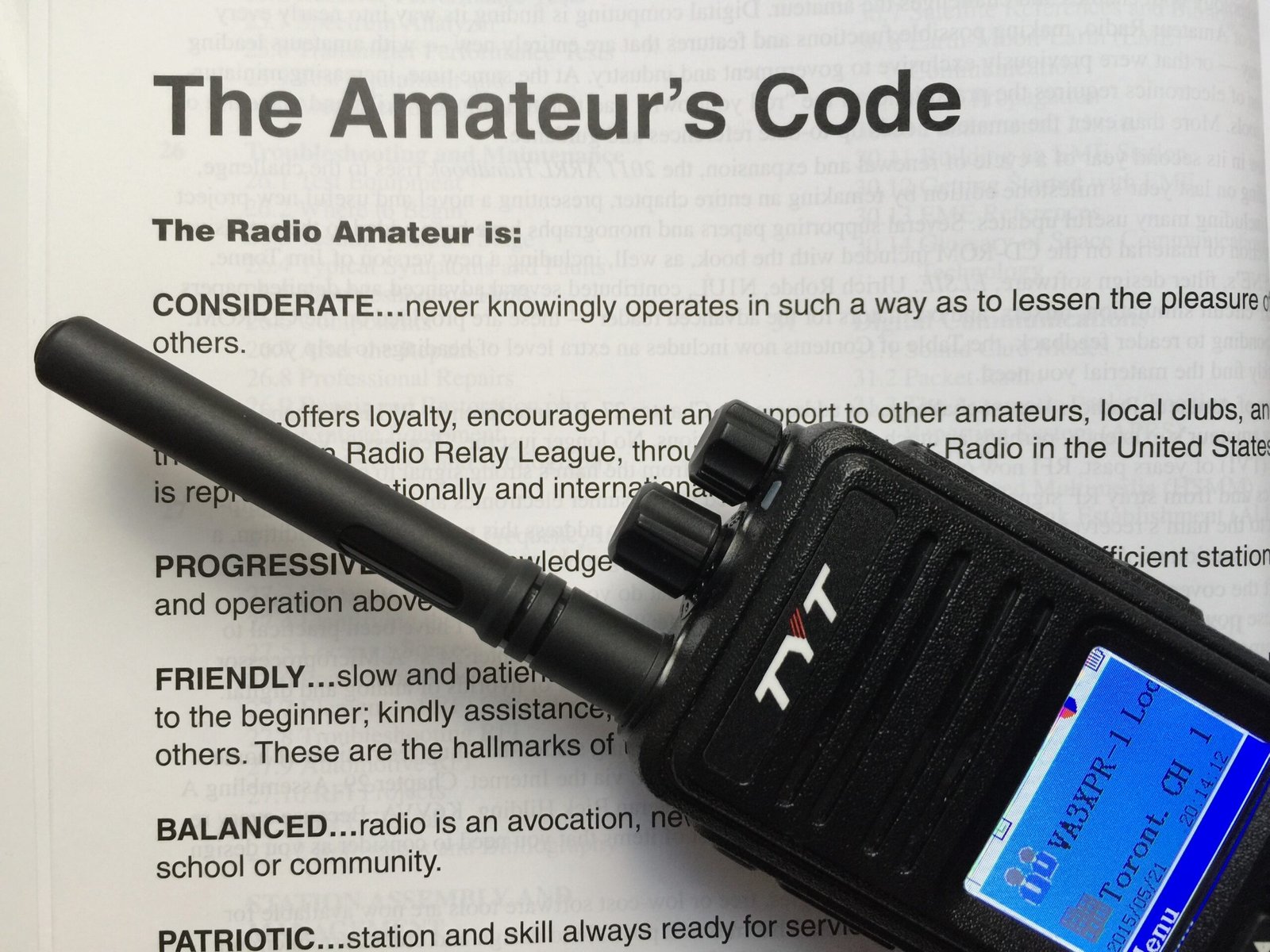 D-STAR for Beginners - handheld DMR radio placed on the Amateur’s Code booklet highlighting on-air etiquette and best practices for ham-radio operators