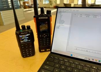 Baofeng DM32UV and AnyTone AT-D878UVII Plus handheld radios beside a laptop running DMR Programming Software.
