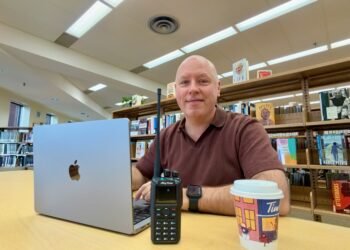 Don Trynor VA3XFT working on EvoHam ham radio digital voice content at a laptop with a DMR handheld radio on the table.