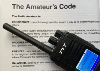 Digital voice handheld radio sitting on top of the original Radio Amateur’s Code document.