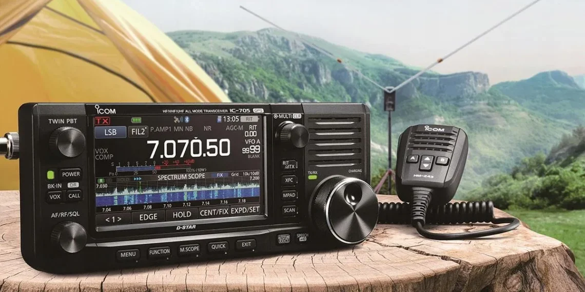 D-STAR for Beginners – Icom IC-705 portable D-STAR radio set up outdoors on a wooden table beside a tent, ready for QRP digital voice operation. Photo credit Icom Inc.